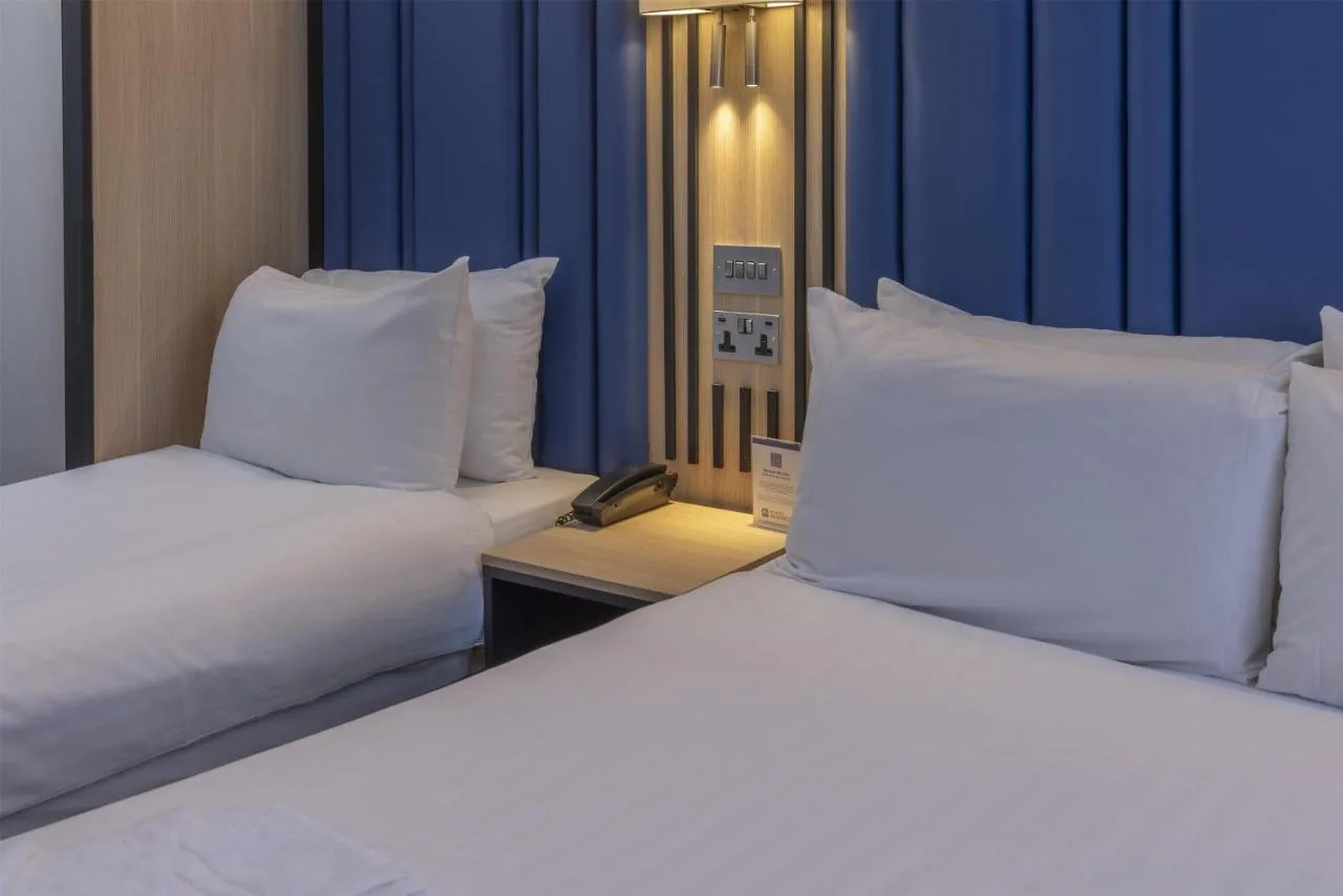 two beds with white pillows in a hotel room at Best Western Victoria Palace in London