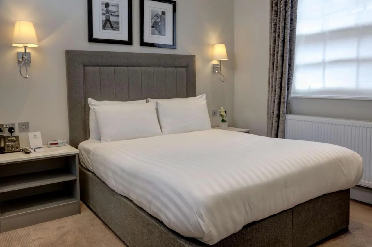 a bedroom with a large bed with white sheets at Best Western Victoria Palace in London